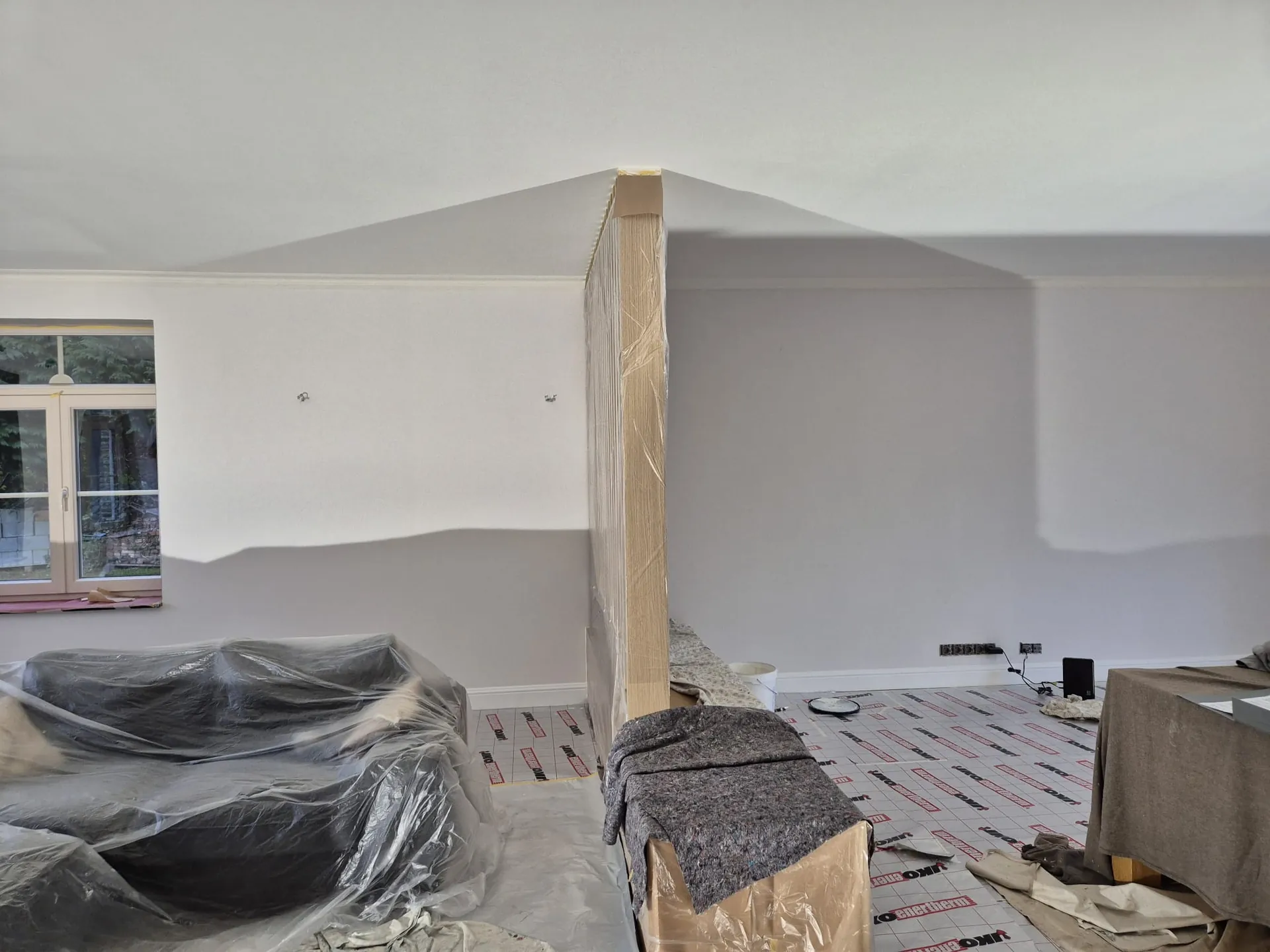 Woonkamer vóór de werken: afgedekte ruimte tijdens het schilderwerk in de Kempen