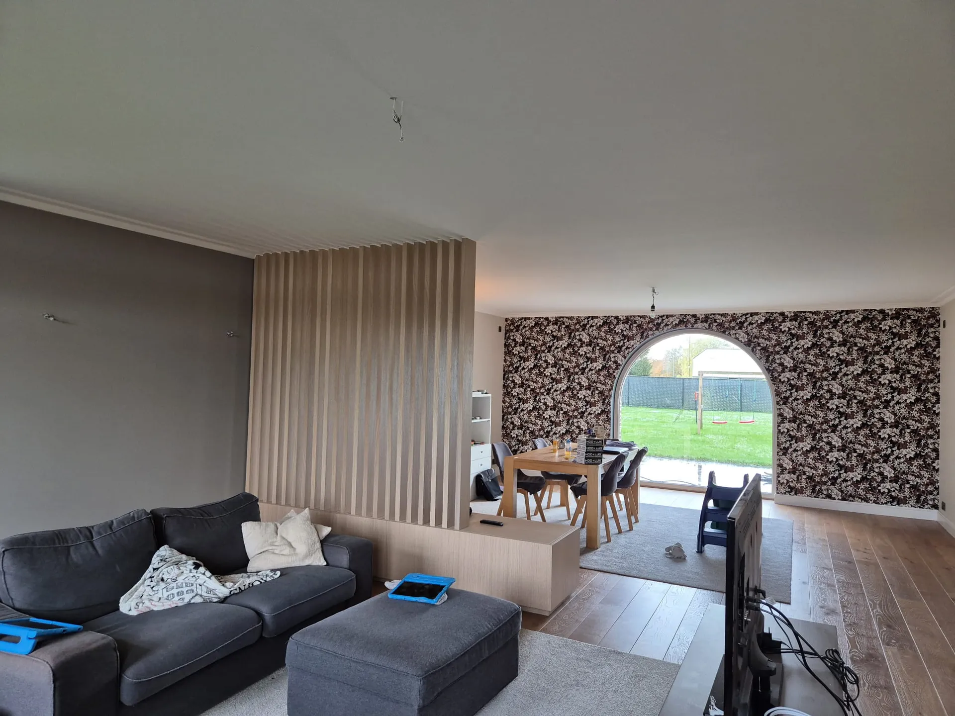 Woonkamer na de werken: geschilderde muren en bloemenbehang rond het boograam in de Kempen