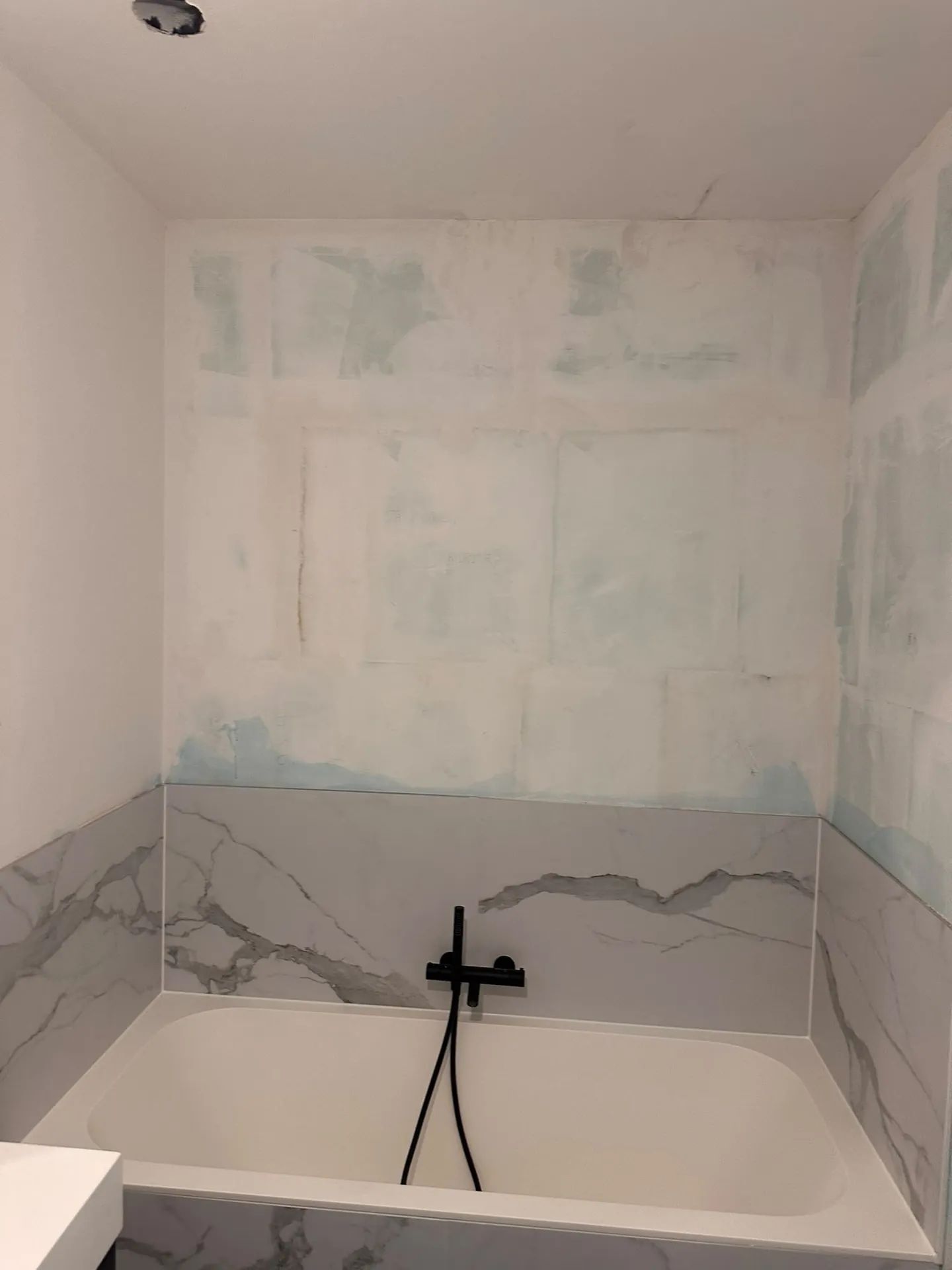 Badkamer vóór de werken: geplamuurde muren boven het bad in de Kempen