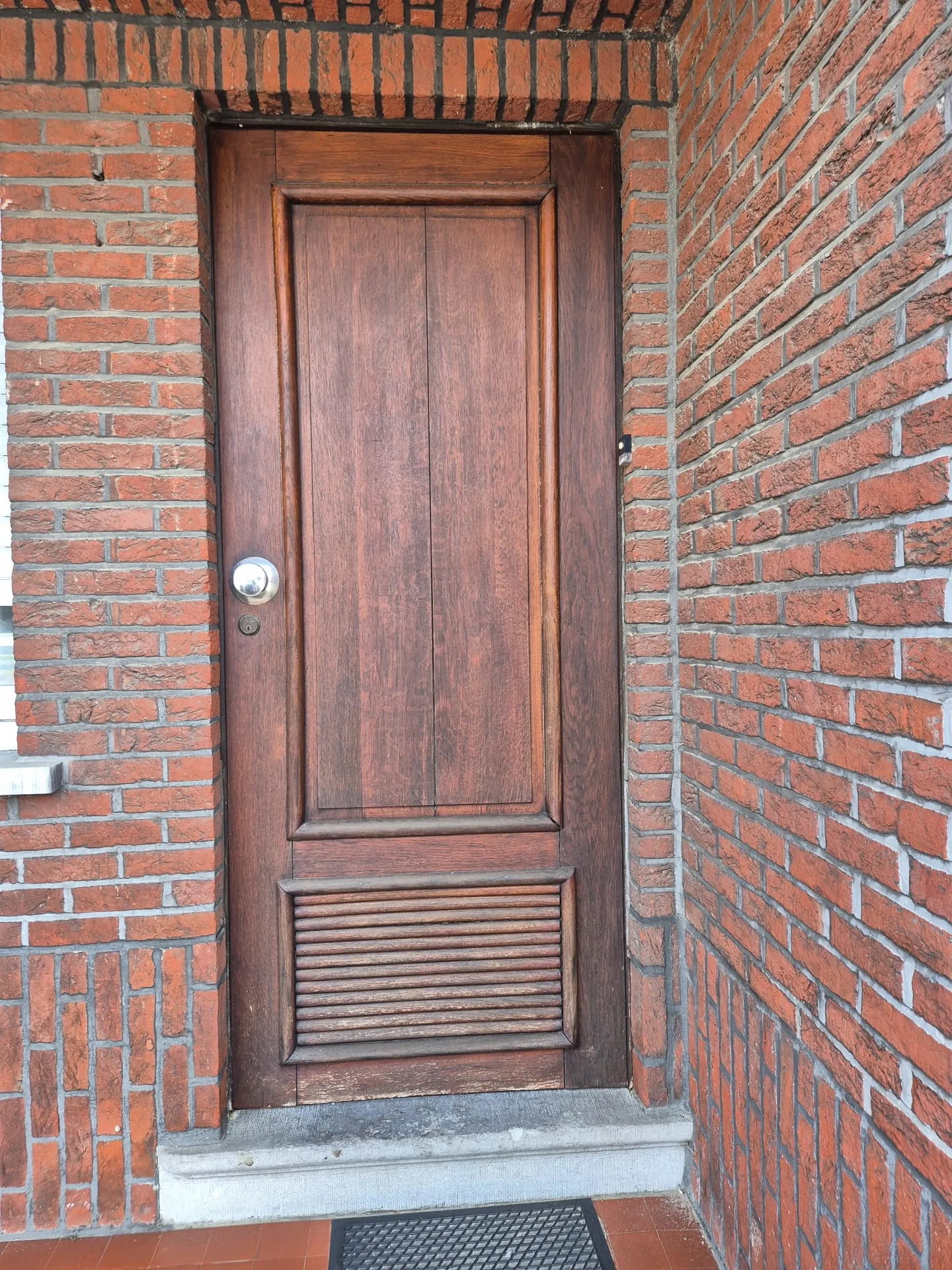 Voordeur vóór de werken: verweerde houten deur in de Kempen
